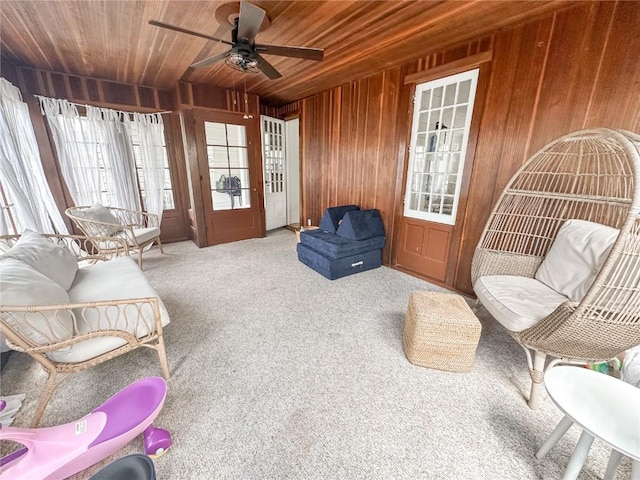 sitting room featuring carpet floors, wood ceiling, wooden walls, and ceiling fan