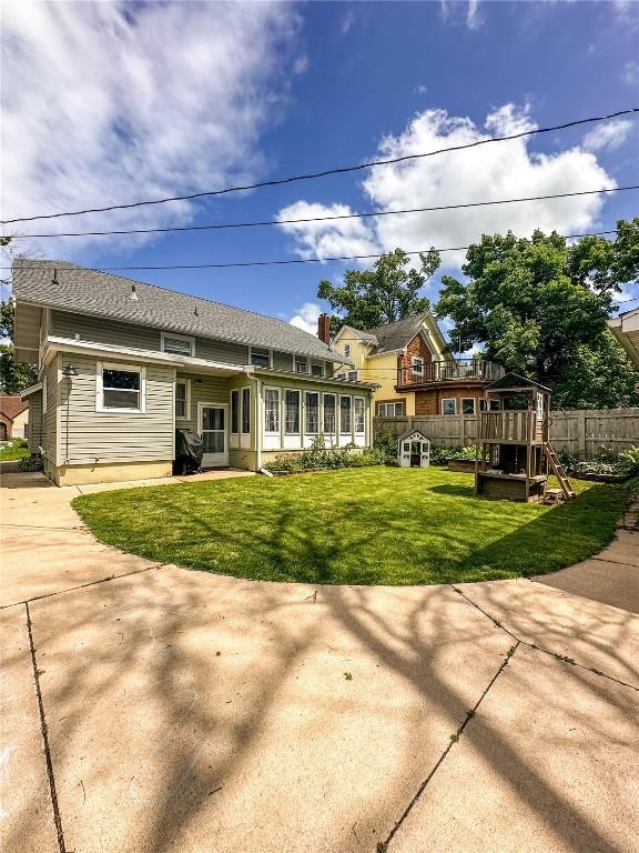 back of property with a yard and a sunroom