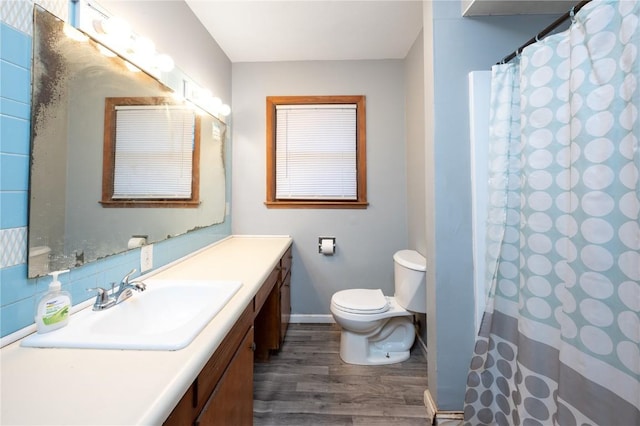 bathroom with hardwood / wood-style flooring, vanity, toilet, and curtained shower