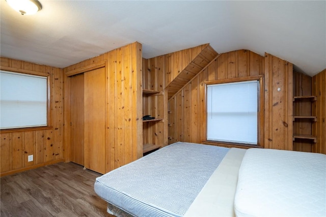 bedroom with hardwood / wood-style flooring, vaulted ceiling, a closet, and wood walls