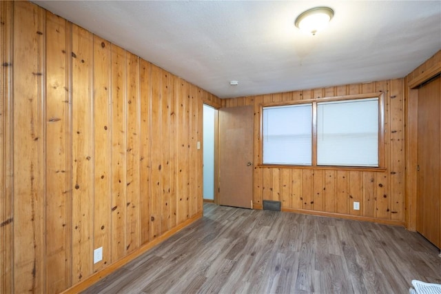 empty room featuring hardwood / wood-style floors and wooden walls