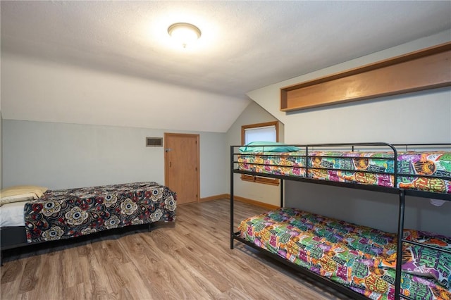 bedroom featuring hardwood / wood-style floors and vaulted ceiling