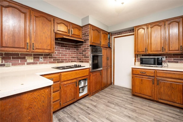 kitchen featuring gas stovetop, backsplash, black oven, and light hardwood / wood-style floors