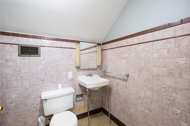 bathroom with sink, tile walls, a textured ceiling, vaulted ceiling, and toilet