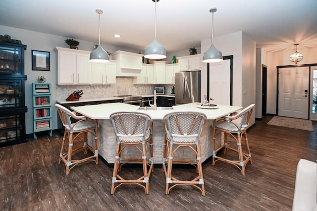 kitchen with white cabinetry, hanging light fixtures, an island with sink, and appliances with stainless steel finishes