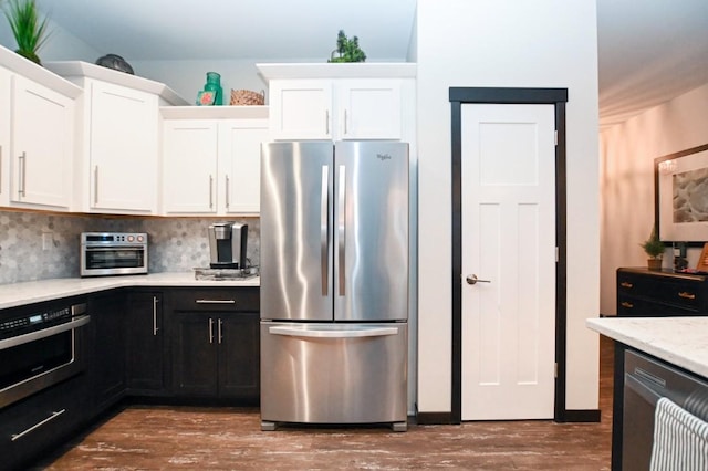 kitchen with white cabinetry, backsplash, stainless steel appliances, dark hardwood / wood-style floors, and light stone counters