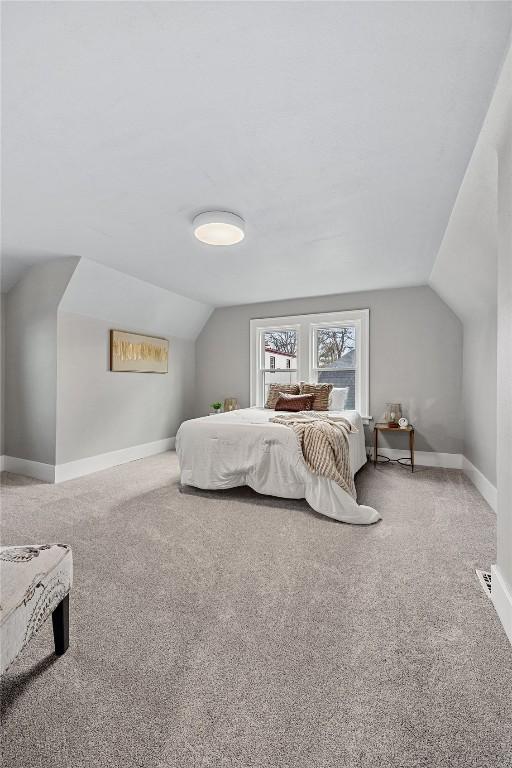 carpeted bedroom with lofted ceiling