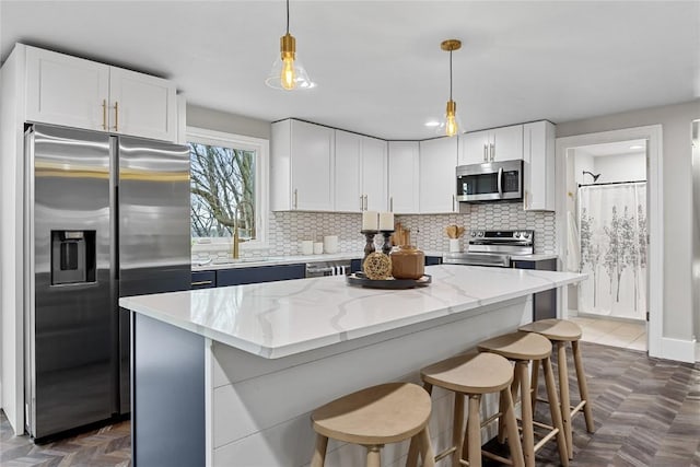 kitchen featuring white cabinetry, appliances with stainless steel finishes, sink, and decorative light fixtures