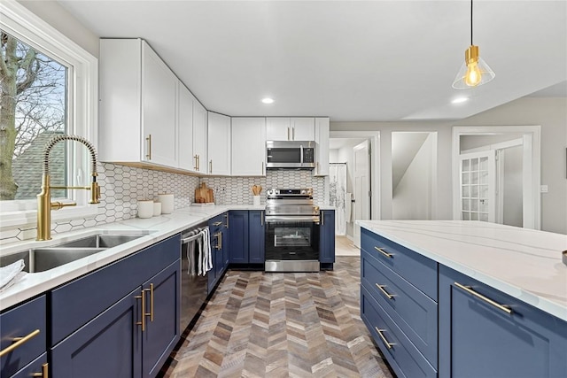 kitchen featuring sink, blue cabinetry, hanging light fixtures, stainless steel appliances, and white cabinets