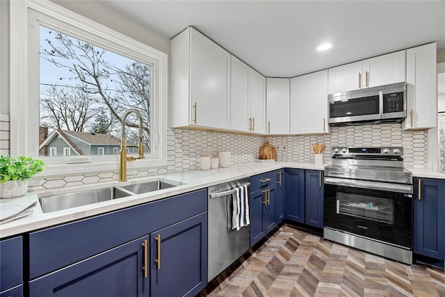 kitchen with stainless steel appliances, white cabinetry, sink, and blue cabinetry