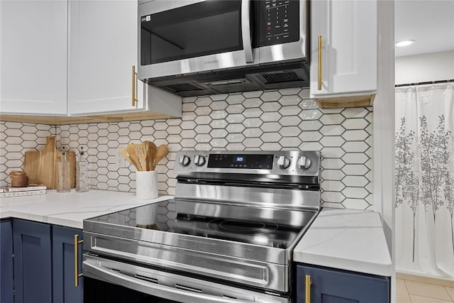 kitchen with appliances with stainless steel finishes, blue cabinets, light stone countertops, and white cabinets