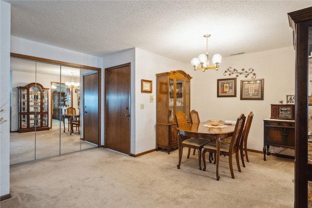 dining room featuring light carpet, a textured ceiling, and a chandelier