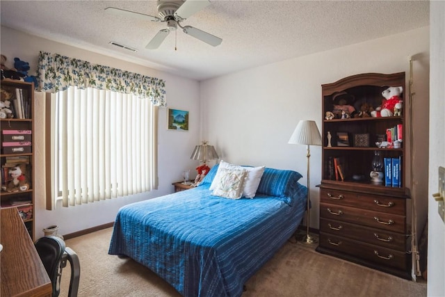 carpeted bedroom with ceiling fan and a textured ceiling