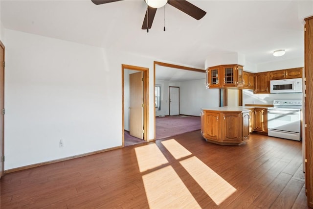 kitchen featuring dark hardwood / wood-style flooring, white appliances, kitchen peninsula, and ceiling fan