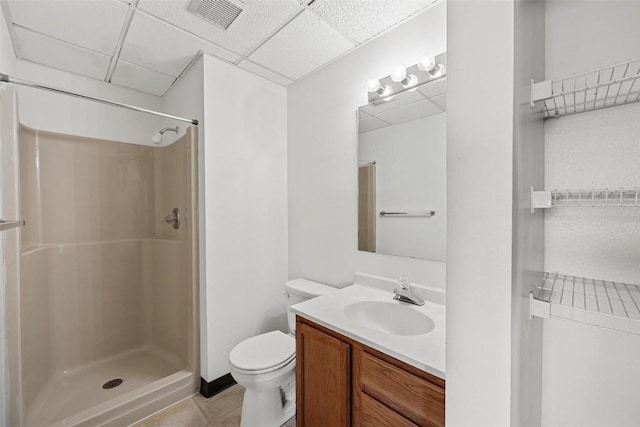 bathroom with a paneled ceiling, tile patterned flooring, vanity, a shower, and toilet