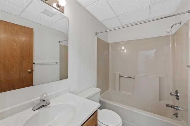 full bathroom featuring vanity, a drop ceiling, shower / bathtub combination, and toilet