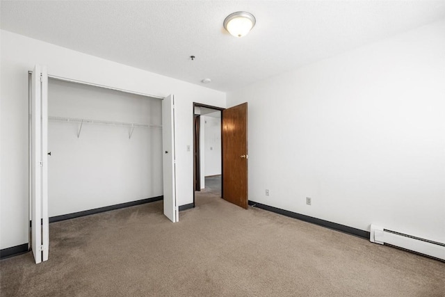 unfurnished bedroom featuring carpet floors, baseboard heating, and a closet