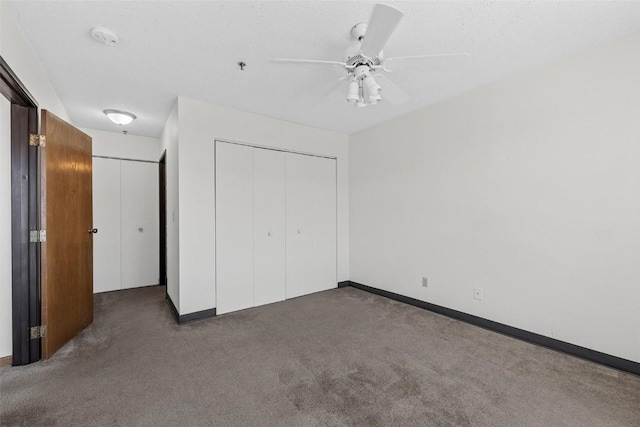 unfurnished bedroom featuring ceiling fan, dark carpet, a closet, and a textured ceiling