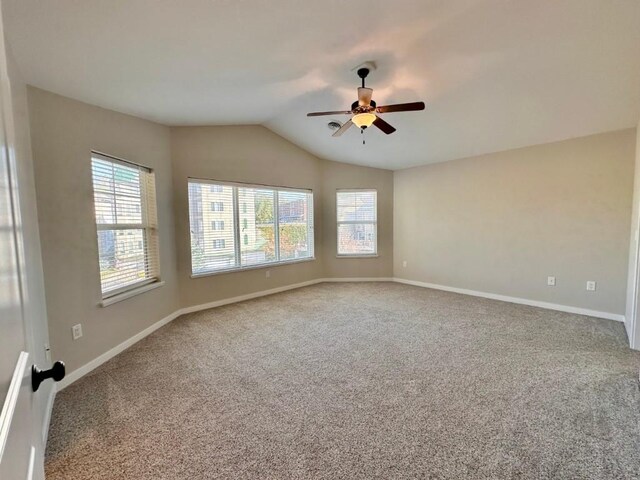 carpeted empty room with ceiling fan, plenty of natural light, and vaulted ceiling