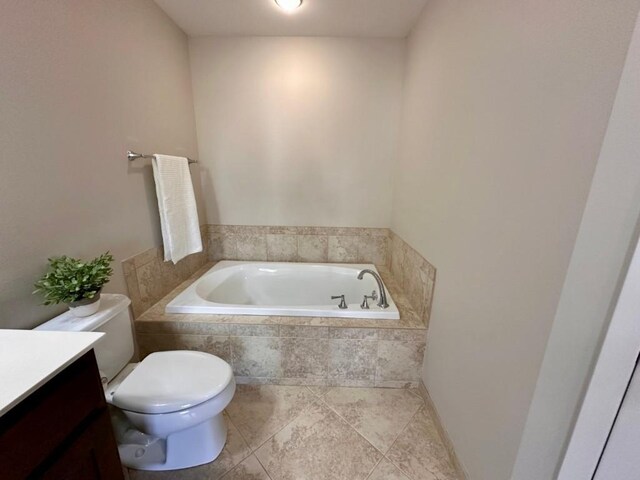 bathroom featuring vanity, a relaxing tiled tub, and toilet