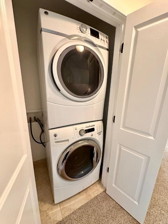 clothes washing area featuring stacked washer and dryer and light tile patterned floors