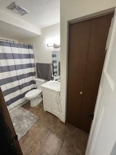 bathroom featuring vanity, toilet, tile patterned flooring, and a textured ceiling