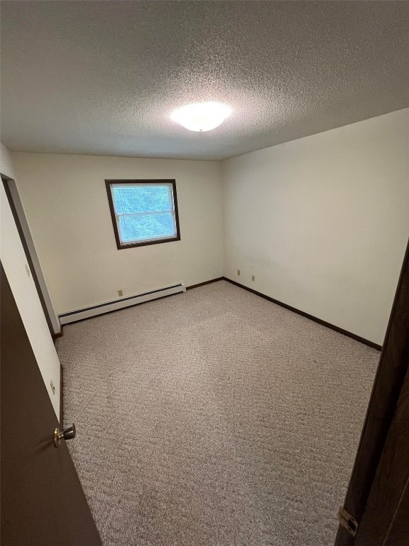 empty room featuring carpet flooring, a textured ceiling, and baseboard heating