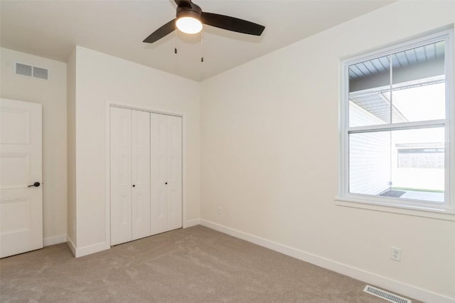 unfurnished bedroom with ceiling fan, light colored carpet, and a closet