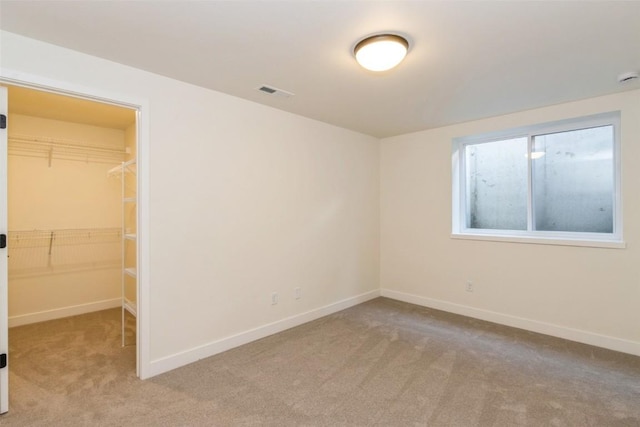 unfurnished bedroom featuring a walk in closet, light carpet, and a closet