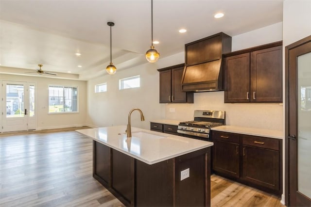 kitchen with sink, premium range hood, hanging light fixtures, dark brown cabinetry, and stainless steel gas range oven