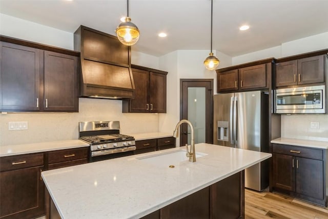 kitchen featuring stainless steel appliances, light stone countertops, sink, and decorative light fixtures