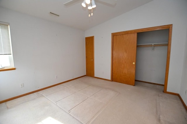 unfurnished bedroom featuring ceiling fan, light colored carpet, lofted ceiling, and a closet