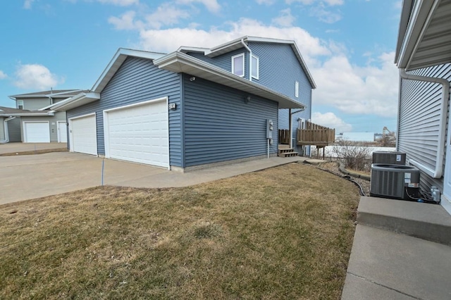 view of home's exterior featuring a garage, a wooden deck, cooling unit, and a lawn