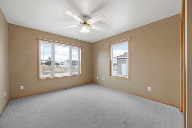 carpeted spare room featuring plenty of natural light and ceiling fan