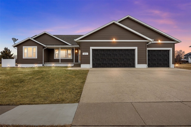 single story home featuring a garage and a lawn