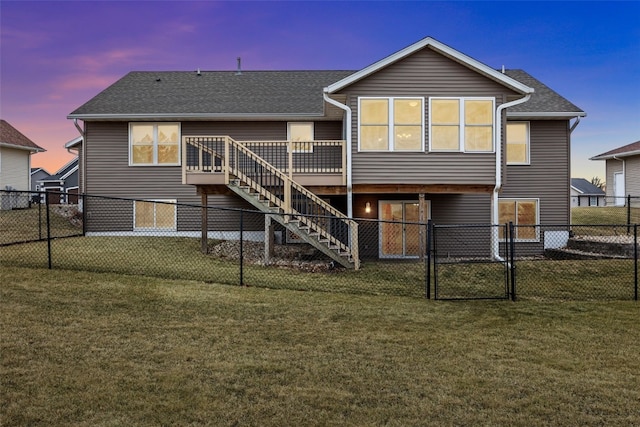 back house at dusk featuring a wooden deck and a lawn