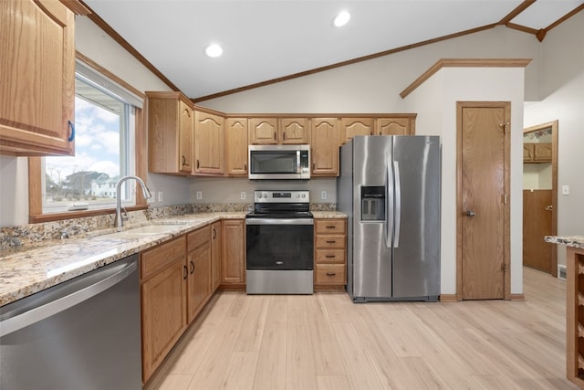 kitchen with vaulted ceiling, appliances with stainless steel finishes, sink, ornamental molding, and light wood-type flooring