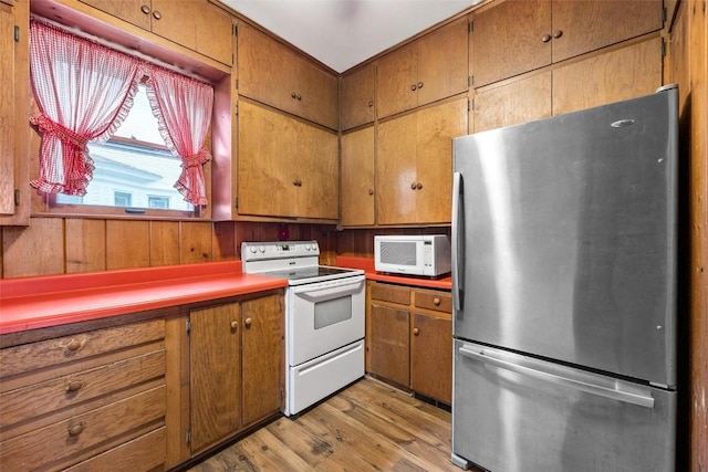 kitchen featuring white appliances, wood walls, and light wood-type flooring