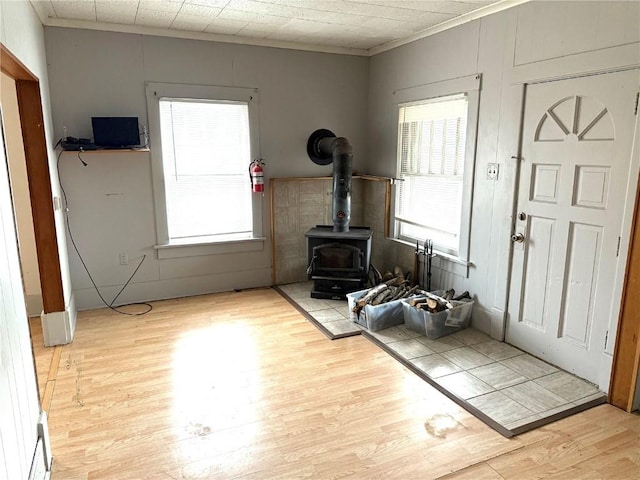 exercise area featuring crown molding, a healthy amount of sunlight, light hardwood / wood-style flooring, and a wood stove