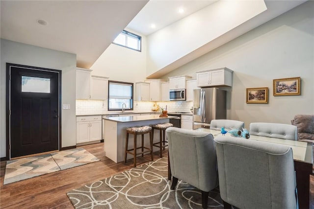 kitchen with a breakfast bar area, stainless steel appliances, a center island, and white cabinets