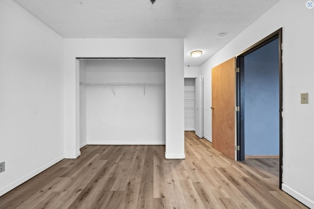 unfurnished bedroom with a closet, wood finished floors, and baseboards