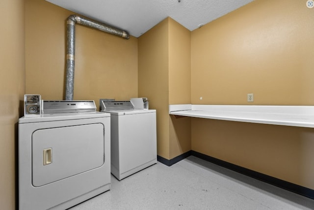 laundry room with a textured ceiling, washing machine and clothes dryer, laundry area, and baseboards