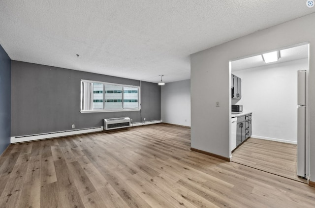 unfurnished living room featuring a baseboard heating unit, light wood-style flooring, baseboards, a textured ceiling, and baseboard heating