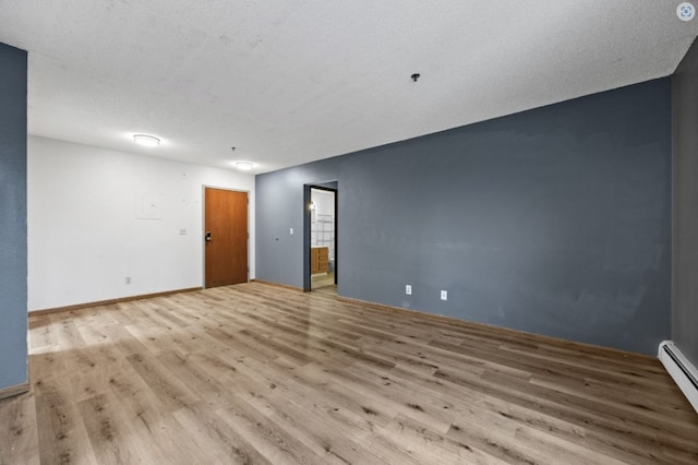 unfurnished room featuring baseboard heating and wood finished floors