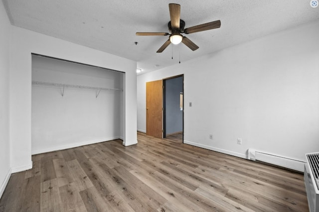 unfurnished bedroom with a baseboard radiator, wood finished floors, and baseboards