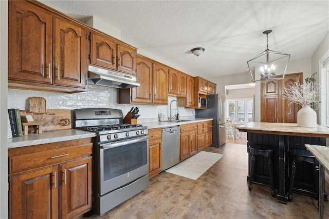 kitchen featuring sink, hanging light fixtures, stainless steel appliances, a textured ceiling, and a chandelier