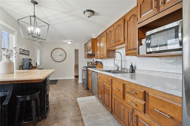 kitchen featuring stainless steel appliances, decorative light fixtures, and sink