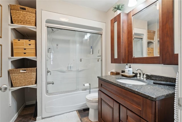 full bathroom with vanity, bath / shower combo with glass door, and toilet