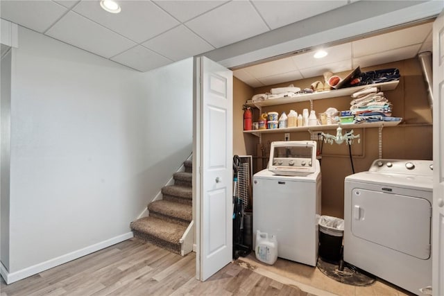 clothes washing area featuring washing machine and dryer and light hardwood / wood-style flooring