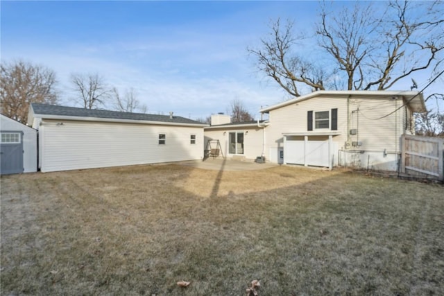 back of house with a storage unit, a patio, and a lawn